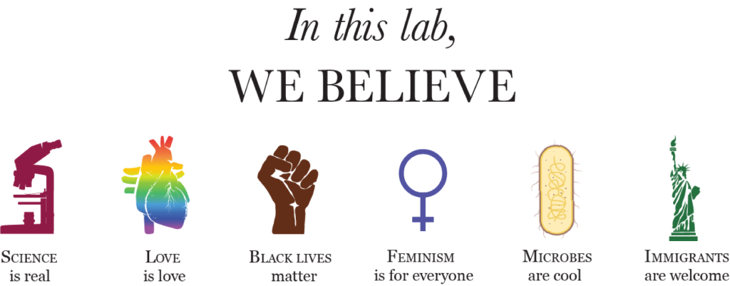 Poster text reads:
In this lab, we believe: science is real (microscope image), love is love (rainbow anatomical heart), black lives matter (brown raised fist), feminism is for everyone (female symbol), microbes are cool (image of a bacterium), immigrants are welcome (statue of liberty).